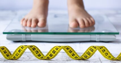 criança em cima da balança indicando sobrepeso e obesidade