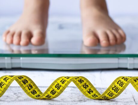 criança em cima da balança indicando sobrepeso e obesidade